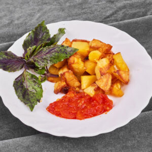 Plat de pommes de terre rôties et sauce tomate servi sur une assiette blanche, cuisine maison