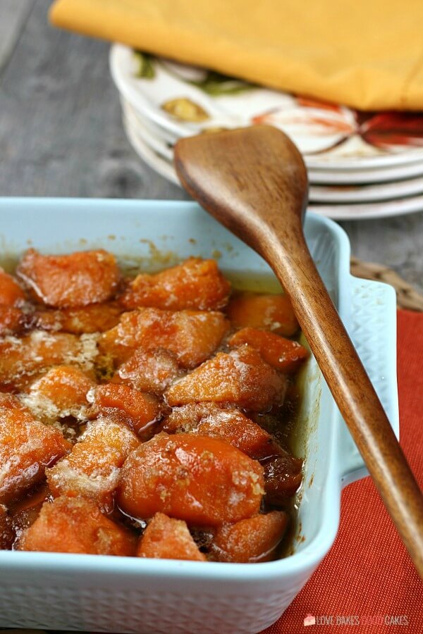 Learn how to make candied yams for your next family meal, it's so simple! This candied sweet potatoes recipe is easy and delicious! Candied Yams in a blue bowl with a wooden spoon.