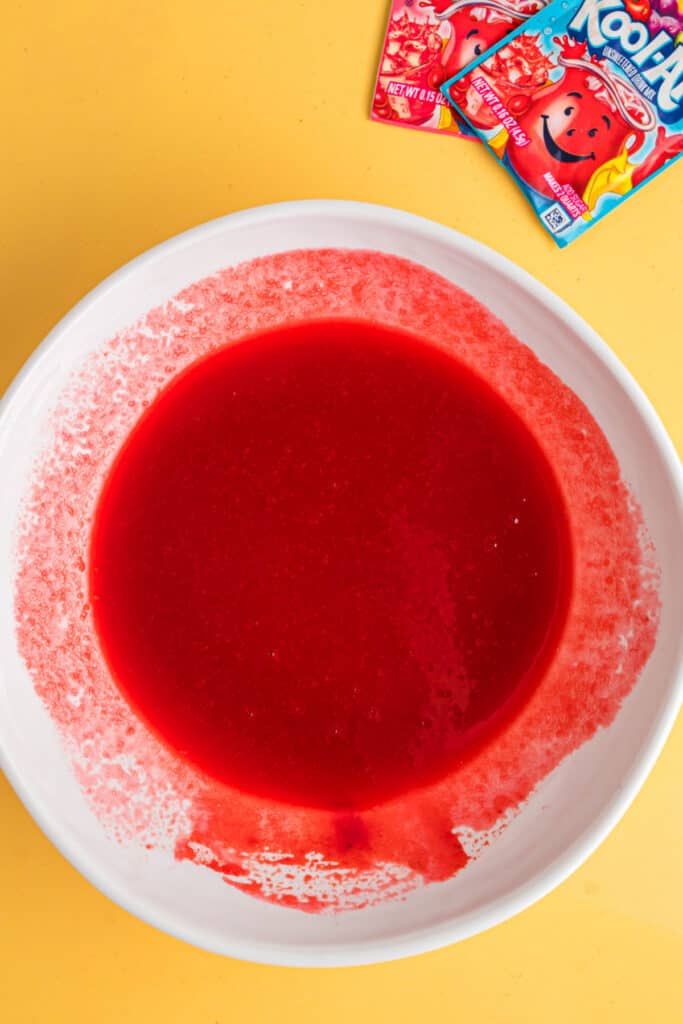 Mélange Kool-Aid rouge vif entièrement combiné dans un bol blanc.