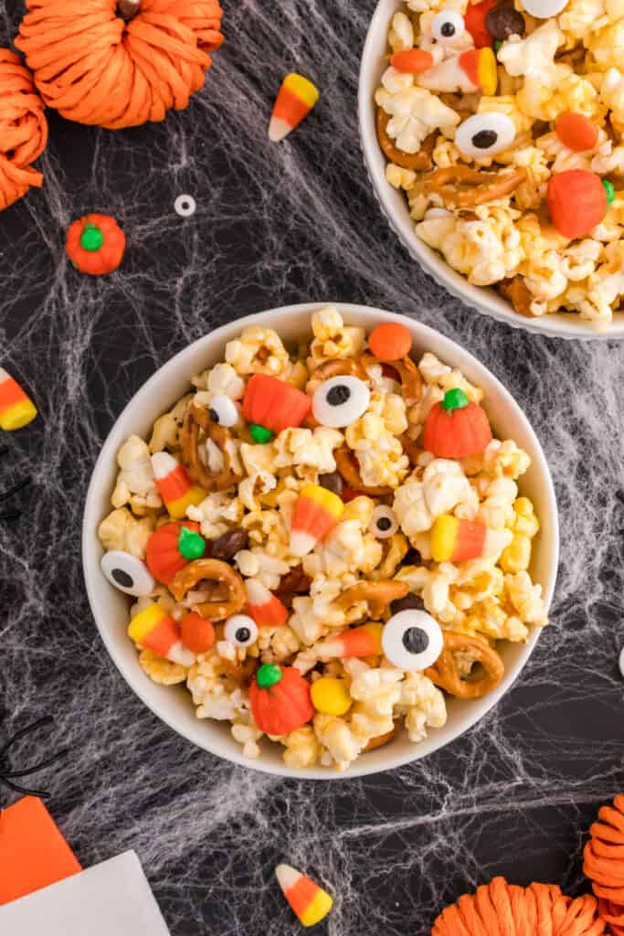 Deux bols de pop-corn Monster Mash avec des globes oculaires et des citrouilles en bonbon sur un fond sur le thème d'Halloween.