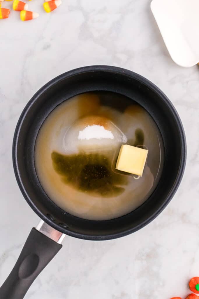 Casserole avec du beurre, du sucre, du miel, de l'eau et de la vanille commençant à fondre pour faire du sirop pour le pop-corn Monster Mash.