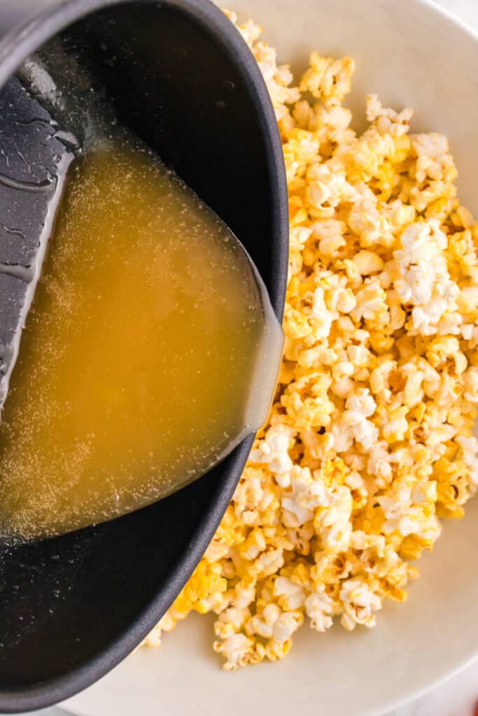 Sirop chaud versé d'une casserole sur un grand bol de pop-corn afin de l'enrober uniformément.